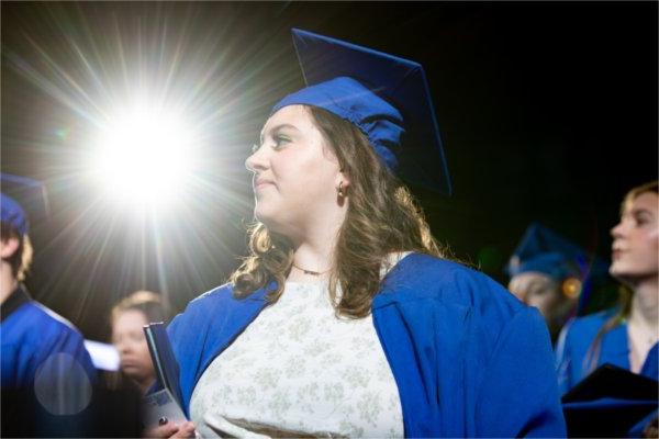 一个穿蓝衣服的毕业生走过一束光. 