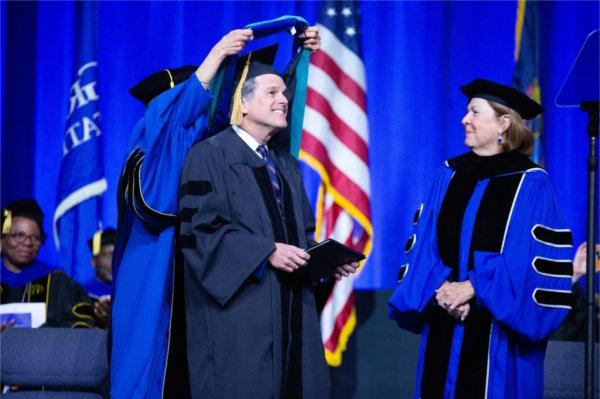  一个人在接受荣誉博士学位时戴着兜帽. 