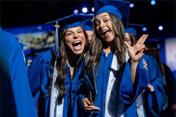   毕业典礼上，毕业生们欢声笑语地跨过舞台，举起手来庆祝. 