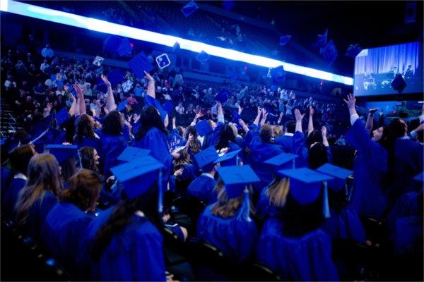  毕业典礼后，毕业生们将他们的蓝帽子抛向空中. 