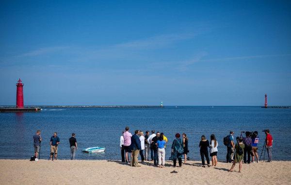 Members of the media watch a drone float on Lake Michigan