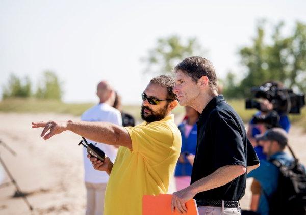 Professors look at a drone skimming along Lake Michigan.